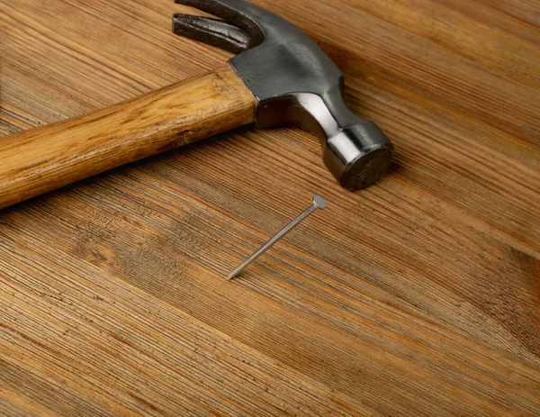 木製の机の上の金属釘とハンマー 木板の鋼釘 茶色の木の背景の建設ハードウェア — ストック写真
