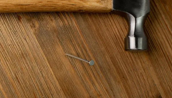 木製の机の上の金属釘とハンマー 木板の鋼釘 茶色の木の背景の建設ハードウェア — ストック写真