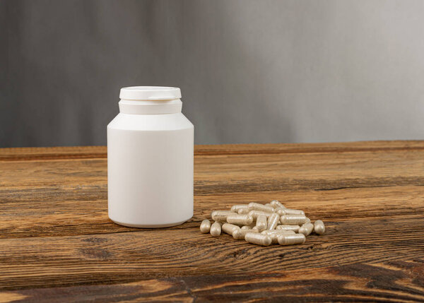 Herbal medicine mockup. Pill bottle on wooden background, traditional medicine capsules, supplement, herb capsule, herbal vitamins, bio supplement bottle with copy space