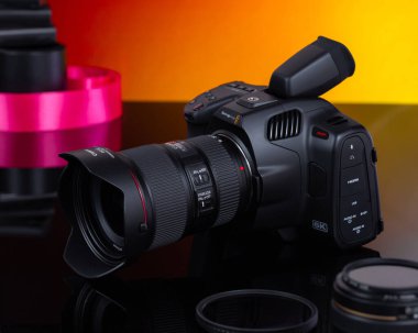 Almaty, Kazakistan, 11 Ekim 2022 - Bulanık turuncu arka planda Canon lensli Blackmagic kamera. Film yapımı, videografi ve ürün fotoğrafçılığı kavramı