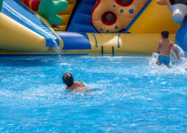 Çocuklar bilardo oynar ve yüzer. İki çocuk bilardoda eğleniyor. Arkadaşlar havuza su sıçratıyor, eğleniyorlar. Yaz tatili kavramı. Yüzme havuzunda oynayan sevimli çocuklar. 