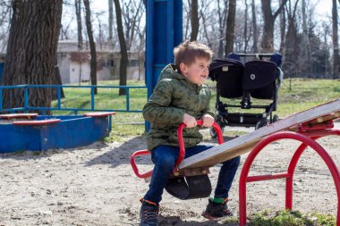 Little boy having fun on swing on playground. Happy child enjoy swinging. Active outdoors leisure for child.