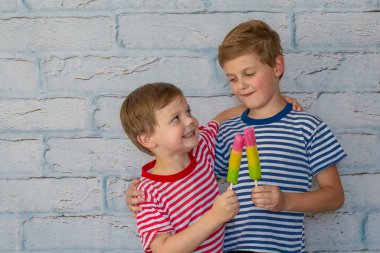 Two happy smiling boys are eating ice cream. Children hugging eat fruit frozen ice