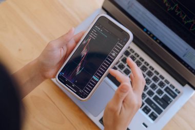 Kadın akıllı telefondan, kripto para birimi gelecekteki fiyat öngörüsünde Bitcoin fiyat tablosunu kontrol ediyor..