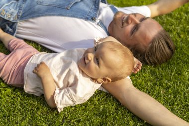 man taking a rest in a garden with his doughter. Spring concept. Family taking a rest in a own garden after work ground. he is wear in overall, baby is smiling, family time