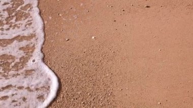 Gün batımında plaj. Sahilde yavaş çekim dalgaları var.