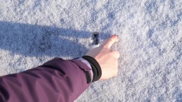 Pige trækker en smiley ansigt på den hvide sne – Stock-video