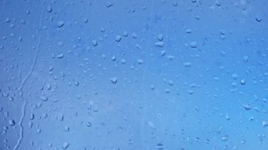 Gökyüzünün arka planında cam üzerine yağmur damlaları