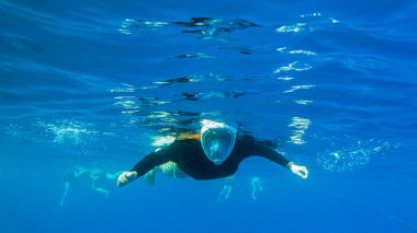 Kız denizde şnorkelle yüzüyor. Maskeli kız suyun altında yüzüyor..