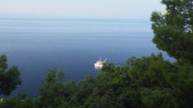 Beyaz bir tur teknesi sahil boyunca ilerliyor.