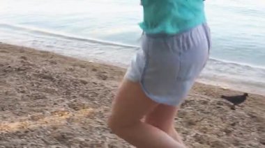 Genç kız kumsalda ağır çekim videoda koşuyor.