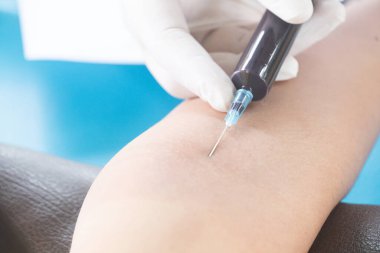 Doktor muayene için hastanın kolundan kan örneği alıyor..