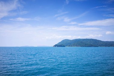 Denizin ortasında bir ada ve denizde yelkenli bir tekne..