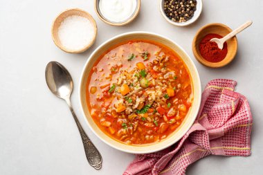 Beton arka planda kaseye biber çorbası doldurulmuş. Üst görünüm.