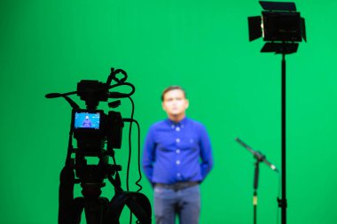 Saratov, Rusya - 4 Eylül 2018: Stüdyoda yeşil arka planda mavi gömlekli bir çocuğun videosu. Chromakey teknolojisi. Tripodun üzerinde bir mikrofon, tripodun üzerinde bir video kamera..