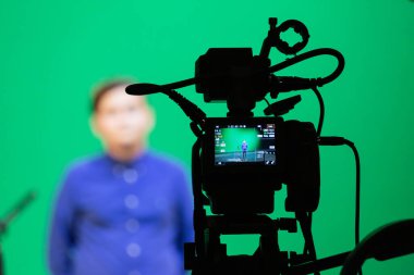 Saratov, Rusya - 4 Eylül 2018: Stüdyoda yeşil arka planda mavi gömlekli bir çocuğun videosu. Chromakey teknolojisi. Tripodun üzerinde bir mikrofon, tripodun üzerinde bir video kamera..