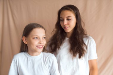 kız kardeşler bej renkli tekstil arka planında eğleniyorlar