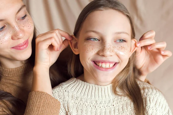 Hermanas abrazándose sobre fondo textil de color beige —  Fotos de Stock