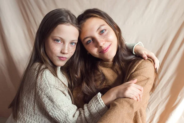 Hermanas abrazándose sobre fondo textil de color beige — Foto de Stock