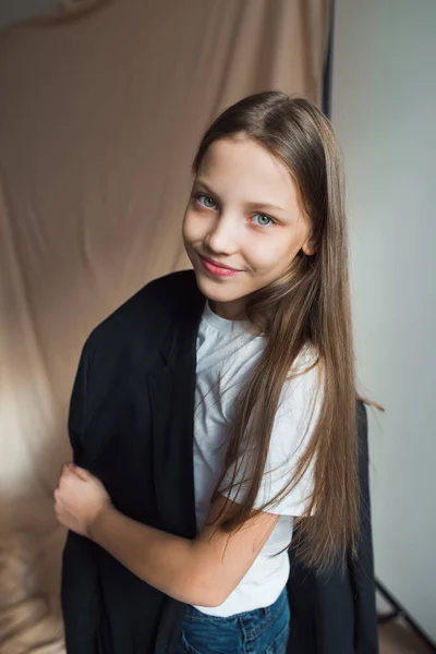 Девушка-модель в черной куртке смеется над студией — стоковое фото