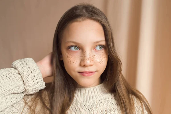 Schöne Teenager-Mädchen mit goldenen Sommersprossen im Gesicht posiert auf beigem Hintergrund — Stockfoto