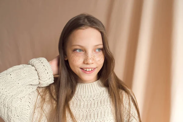 Beautiful teenage girl with golden freckles on face posing on beige background — 图库照片