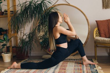 Kadın içeride yerde esneme egzersizleri yapıyor.