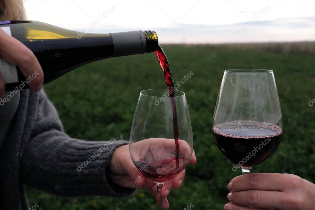 glass and bottle of red wine outdoors, pouring drinks into a glass