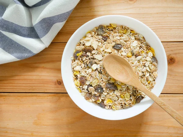 A Bowl of muesli breakfast and rolled oats with dried fruits on wooden table. Top view.