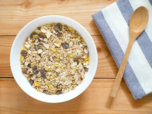 A Bowl of muesli breakfast and rolled oats with dried fruits on wooden table. Top view.