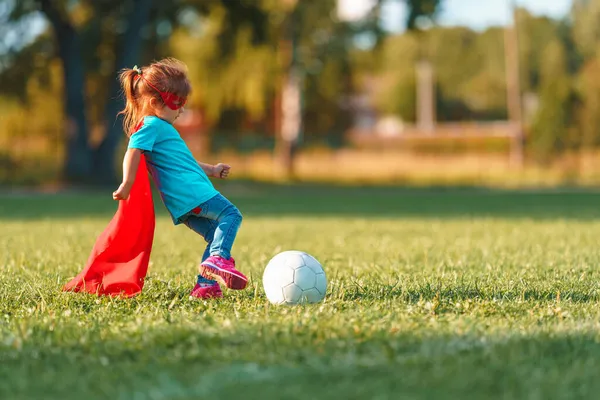 Маленькая Девочка Костюме Супергероя Играет Футбол Свежем Воздухе Счастливая Девушка — стоковое фото