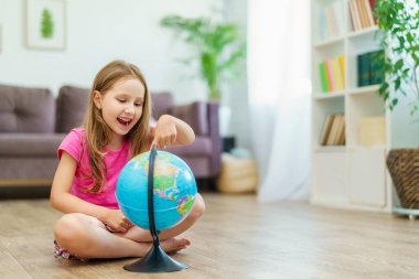 Küçük mutlu bir Kafkasyalı kız evde yerde oturan dünyanın bir taklidine bakıyor. Meraklı bir liseli kız ödevini yapar ve cevabı dünyaya gösterir..