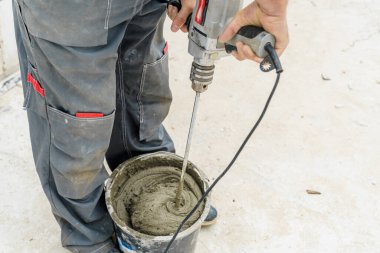 Genç erkek tuğla ustası beton yoğuruyor, havalanan beton bloklar döşemek için, inşaat alanında bir mikser kullanarak. Metin için boş alan. Boşluğu kopyala
