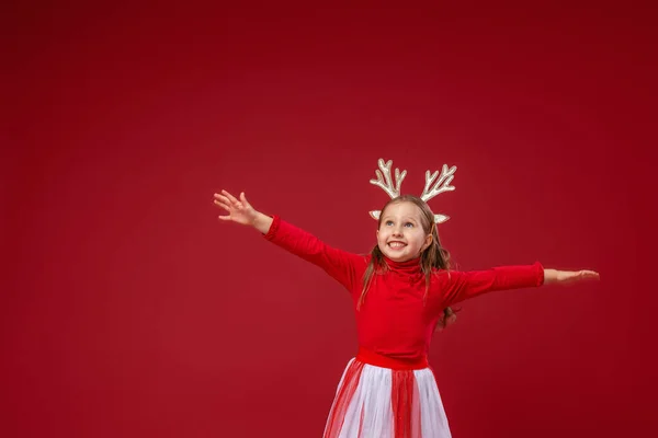 黄金のトナカイの釣り人の幸せな面白い女の子が走り クリスマスの日にスタジオで赤の背景にジャンプします 子供は走り 完全に成長してジャンプする ダイナミックイメージ スペースのコピー — ストック写真