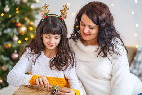 圣诞快乐 节日快乐 快乐的妈妈和女儿拥抱在一起 把圣诞礼品盒放在装饰着花环的圣诞树上 靠近点 — 图库照片