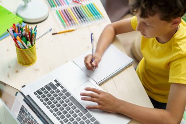 Neşeli beyaz çocuk öğretmeniyle video görüşmeleri için dizüstü bilgisayar kullanıyor. Çocuk uzaktan öğrenmekten hoşlanıyor. O, bilgi almaktan mutlu. E-Eğitim Mesafesi Öğrenme, Ev Eğitimi.