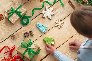 Mutlu Noeller ve mutlu tatiller. Bir kadın hediye paketliyor, evdeki masada kutulara kurdele bağlıyor. Tatil için hazırlanıyorum. Üst görünüm