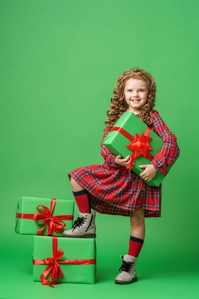 可爱的小女孩 卷曲的头发 金鹿角 站在工作室的绿色背景礼品盒 孩子高兴地微笑着 看着镜框 复制空间 — 图库照片