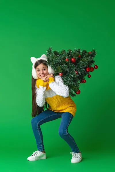 身穿针织毛衣 头戴毛皮耳机 肩上挂着红色圣诞彩球的快乐少女 背着粉色背景走路 动态图像 免版税图库照片