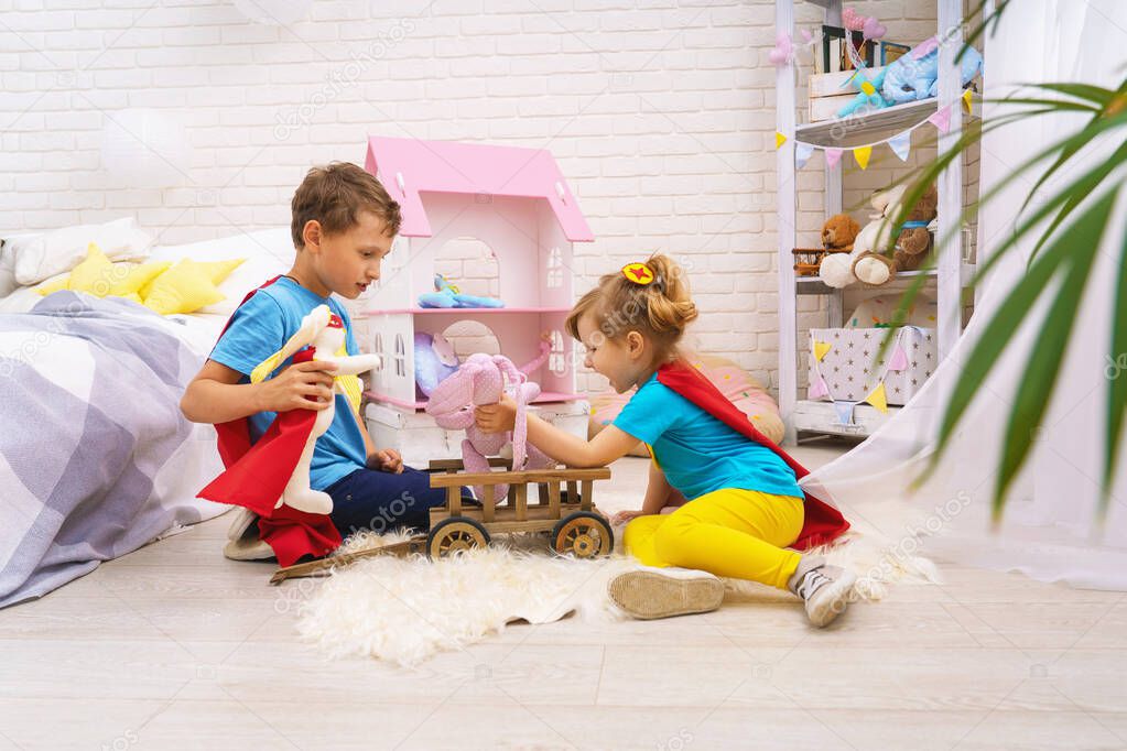 Funny children play with toys in superheroes, in children room. Kids play superhero with Cape and mask at home, saving world and fighting evil. concept protectors and saviors in person small child.