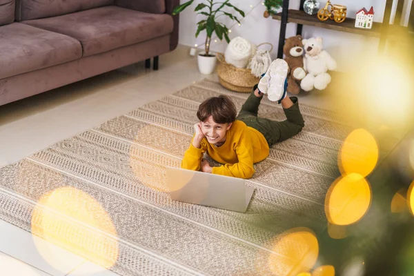 Маленький Хлопчик Жовтому Светрі Лежить Животі Посміхається Дивиться Монітор Ноутбука — стокове фото