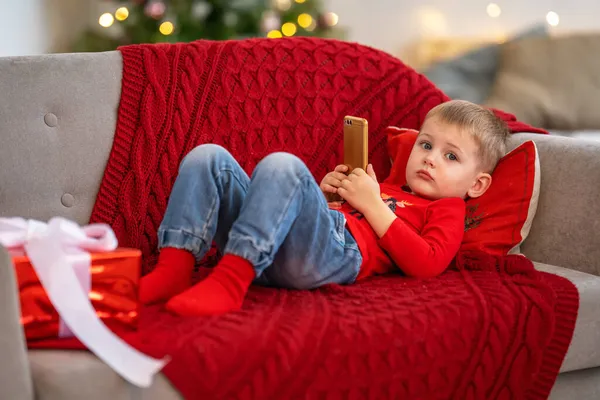 Niño Pequeño Juega Con Dispositivo Técnico Solo Niño Mira Pantalla Imagen de stock