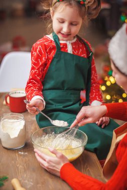 Mutlu noeller. Kızım annemin yemek yapmasına yardım eder. Aile yemekleri şenlikli yemekler. Anne ve kızı Noel kurabiyesi yapıyorlar. İyi tatiller. Akşam vakti, mutlu aile mutfakta..