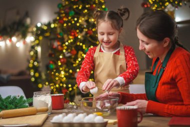 Mutlu noeller. Kızım annemin yemek yapmasına yardım eder. Aile yemekleri şenlikli yemekler. Anne ve kızı Noel kurabiyesi yapıyorlar. İyi tatiller. Akşam vakti, mutlu aile mutfakta..
