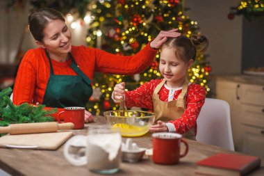 Mutlu noeller. Kızım annemin yemek yapmasına yardım eder. Aile yemekleri şenlikli yemekler. Anne ve kızı Noel kurabiyesi yapıyorlar. İyi tatiller. Akşam vakti, mutlu aile mutfakta..