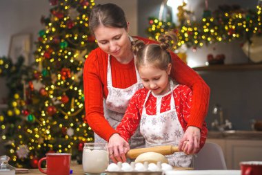 Mutlu noeller. Kızım annemin yemek yapmasına yardım eder. Aile yemekleri şenlikli yemekler. Anne ve kızı Noel kurabiyesi yapıyorlar. İyi tatiller. Akşam vakti, mutlu aile mutfakta..