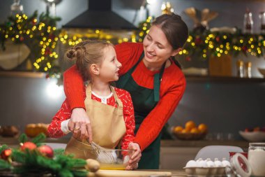 Mutlu noeller. Kızım annemin yemek yapmasına yardım eder. Aile yemekleri şenlikli yemekler. Anne ve kızı Noel kurabiyesi yapıyorlar. İyi tatiller. Akşam vakti, mutlu aile mutfakta..