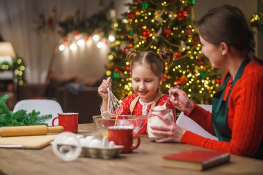 Mutlu noeller. Kızım annemin yemek yapmasına yardım eder. Aile yemekleri şenlikli yemekler. Anne ve kızı Noel kurabiyesi yapıyorlar. İyi tatiller. Akşam vakti, mutlu aile mutfakta..