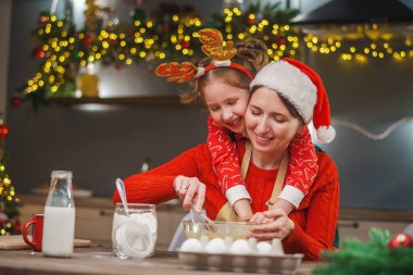 Mutlu noeller. Kızım annemin yemek yapmasına yardım eder. Aile yemekleri şenlikli yemekler. Anne ve kızı Noel kurabiyesi yapıyorlar. İyi tatiller. Akşam vakti, mutlu aile mutfakta..