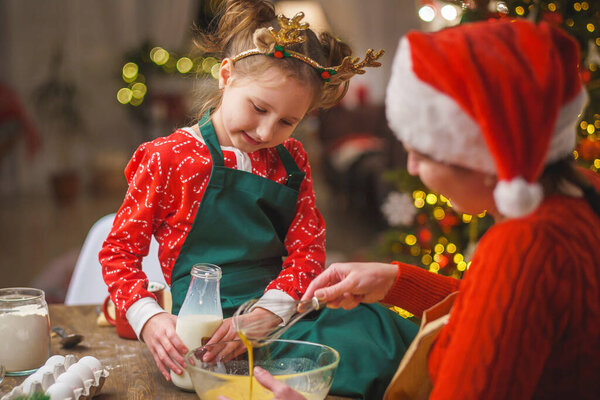 Merry Christmas. My daughter helps my mother cook. Family cooking of festive food. Mother and daughter are making Christmas cookies. happy holidays. Evening time, happy family in the kitchen.